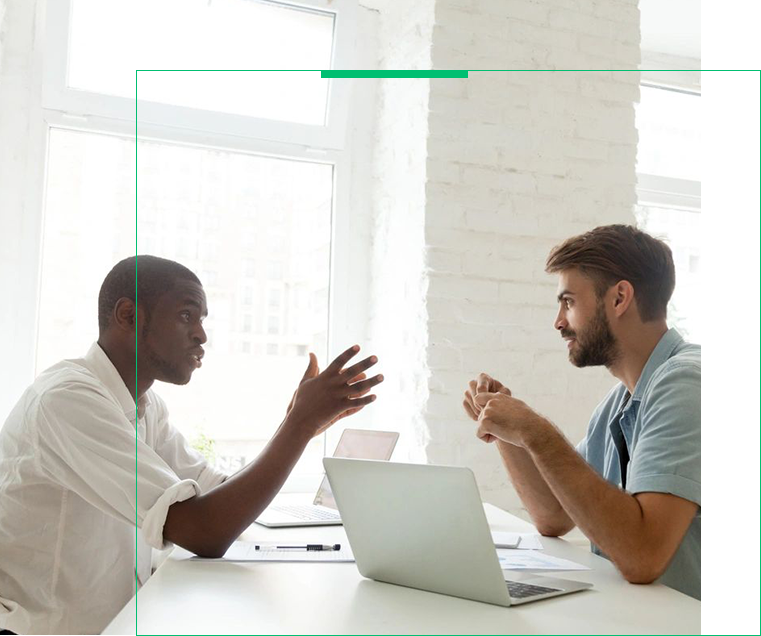 Two men sitting at a table with laptops